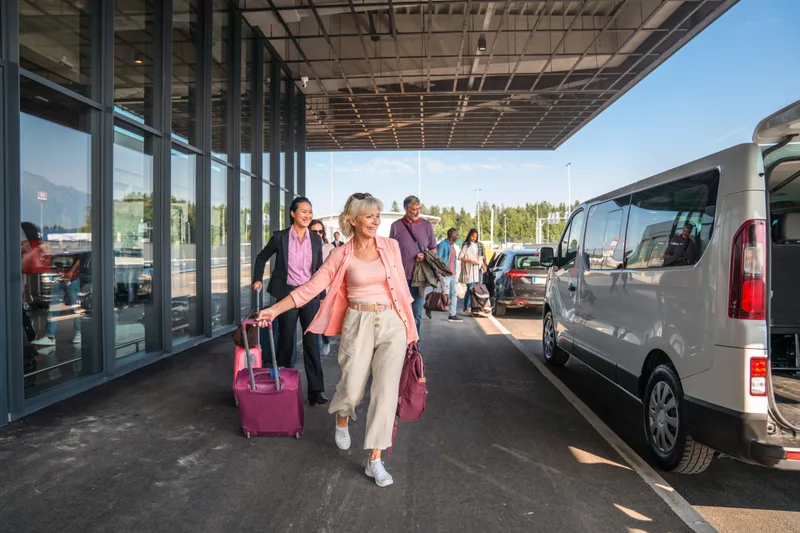 A group and luggage boarding a Sprinter Van